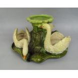 An early 20th century Bretby table centre piece modelled as three swans in a lake, with impressed