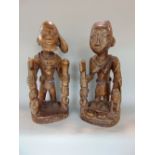 A pair of Benin type carved African tribal figures of a tribesman and his partner, both holding
