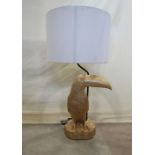 A decorative contemporary novelty standard lamp in the form of a toucan perched on a naturalistic
