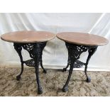 A pair of traditional cast iron pub tables with female face mask and decorative pierced detail