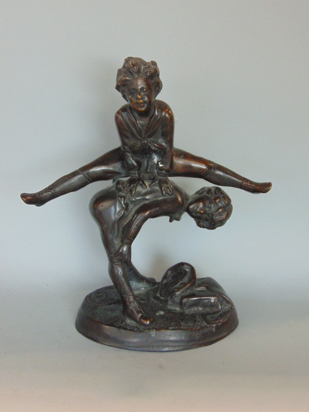 Cast bronze character group of two boys playing leap frog, 25cm high