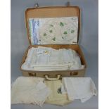 Suitcase filled with collection of vintage table linen including lacework mats, damask cloths,