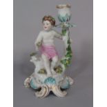 A candlestick in the Chelsea manner with applied figure of a cherub, with floral garland raised on a