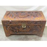 An Eastern camphor wood chest with profusely carved detail, brass lock plate, hinged lid and stepped