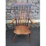 A Windsor stained elm and beechwood lathe back armchair raised on turned supports and stretchers;