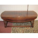 A low oak old English style oval drop leaf occasional table raised on turned supports united by