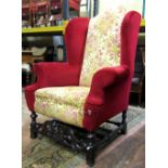 A substantial Carolean style wing armchair with scrolled arms raised on polished walnut showwood