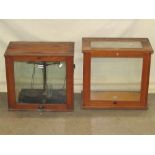 An oak cased laboratory scale, with glazed surround and rise and fall sliding front, together with a