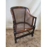 An early 20th century stained beechwood framed bergere chair with horseshoe shaped back raised on