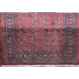 Bokhara full pile carpet with typical geometric decoration upon a washed red ground, 270 x 190cm