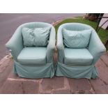 A pair of tub chairs with green patterned loose covers