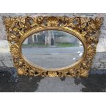 A gilt framed wall mirror, the oval plate set within a scrolling acanthus and shell frame, 95 x