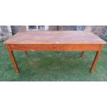 A pine farmhouse kitchen table, the rectangular top with rounded corners over a central frieze