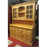 A stripped pine kitchen dresser, the base enclosed by three panelled doors and three drawers beneath