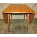 An Ercol light elm drop leaf dining table with moulded outline raised on splayed legs together