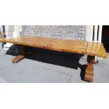 A substantial rustic cedar refectory table, the boarded top raised on a pair of carved pineapple