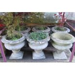 Six matching weathered cast composition stone garden urns of squat circular form, with flared