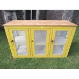 An old vintage pine floorstanding meat safe/food cupboard with yellow painted finish enclosed by