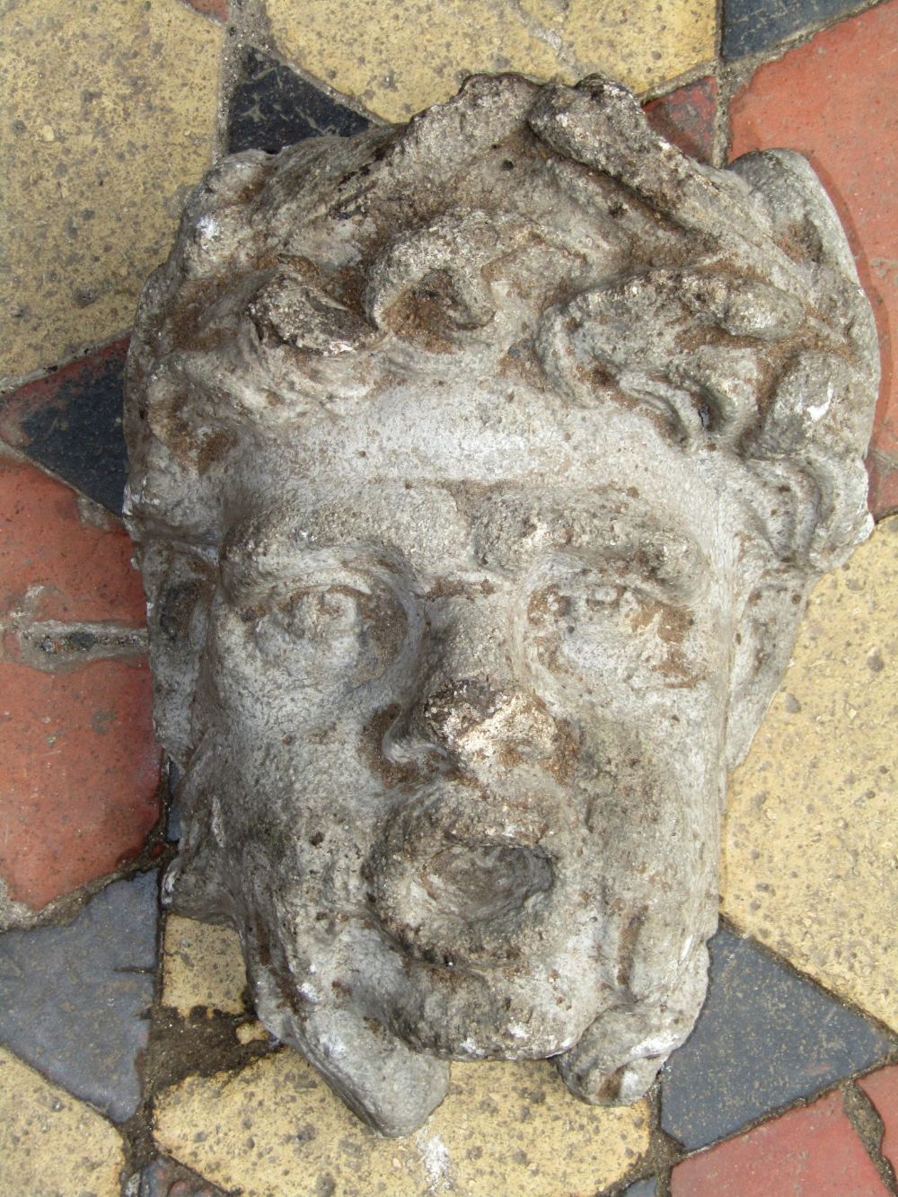 A weathered composition stone wall mounted face mask 32 cm in height