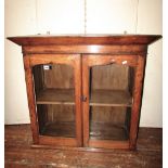 An early 19th century Welsh oak hanging cupboard, enclosed by a pair of glazed panelled doors,