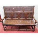 A 17th century oak settle with carved and panelled back work including lozenges, repeating geometric