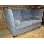 A traditional knoll two seat sofa, with pale blue upholstery, typical drop arms, tie backs and loose