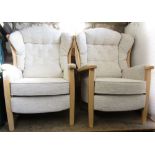 A pair of contemporary beechwood wing back chairs with pale cream upholstered finish by the Relax