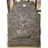 A cast iron fire back, of stepped arched form, with raised relief detail of a cherub astride a