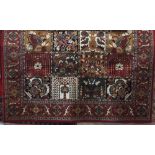 Belgian type rug decorated with various floral panels upon a red ground, 320 x 240 cm