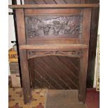 A substantial oak fire surround with pegged frame, the raised back with carved panel of a harvesting