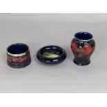 Three pieces of Moorcroft pottery wares comprising a pomegranate pattern vase, with impressed and