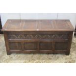 An oak blanket box in the form of an Old English style oak coffer with panelled frame and carved