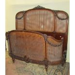 A 19th century continental walnut bergere panel, double bedstead with well carved floral swag