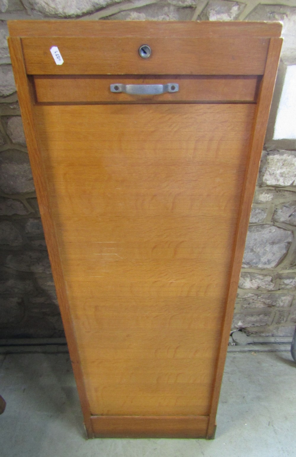 An oak framed floor standing pedestal filing cabinet enclosed by a rise and fall tambour door, the