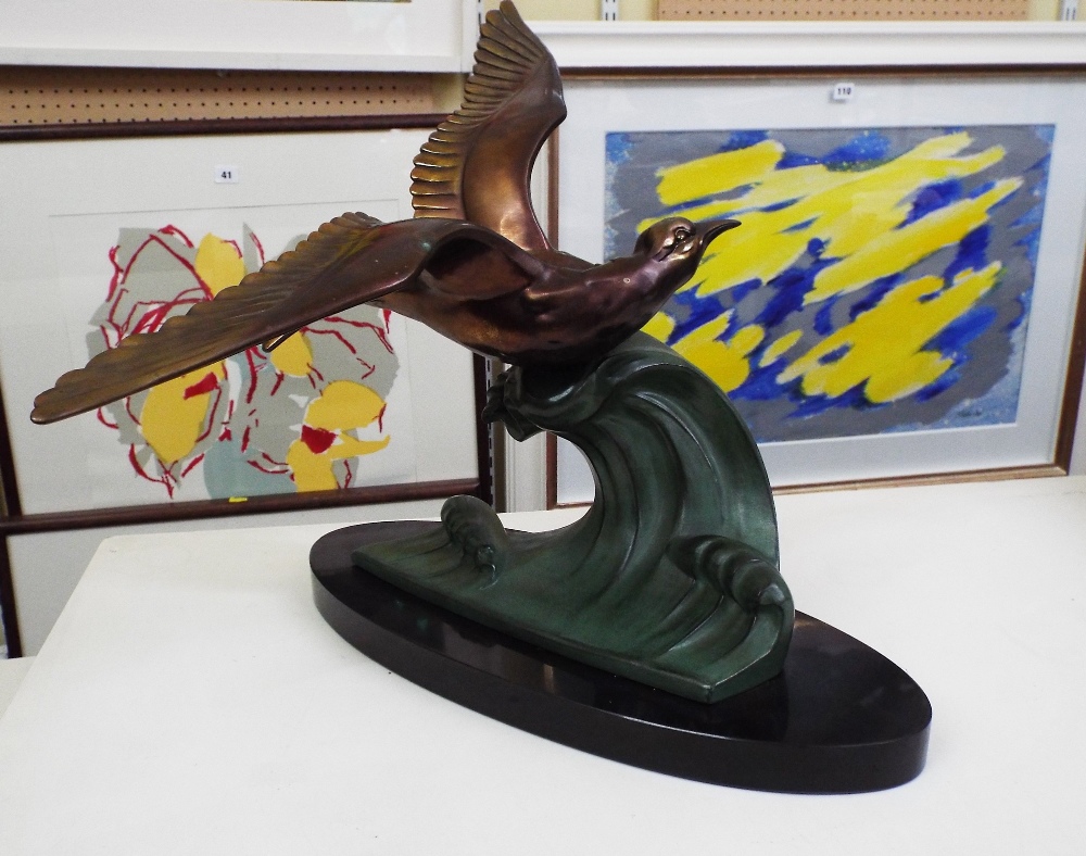 Art Deco gilt and verdigris spelter character group of a flying bird on a wave, upon an oval