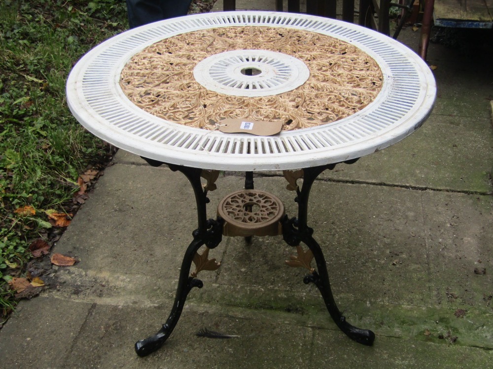 A cast aluminium garden terrace table of circular form with decorative pierced scrolling foliate and