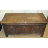 An oak blanket chest in the form of an early oak coffer, with hinged lid, panelled frame and linen