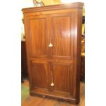 A Georgian mahogany freestanding corner cupboard enclosed by two panelled doors on short bracket