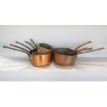 Thirteen various graduated copper saucepans with steel handle and tinned interiors