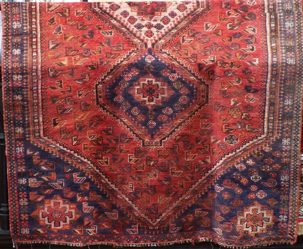 Middle Eastern rug with three central medallions framed by further Paisley scrolls upon a washed red