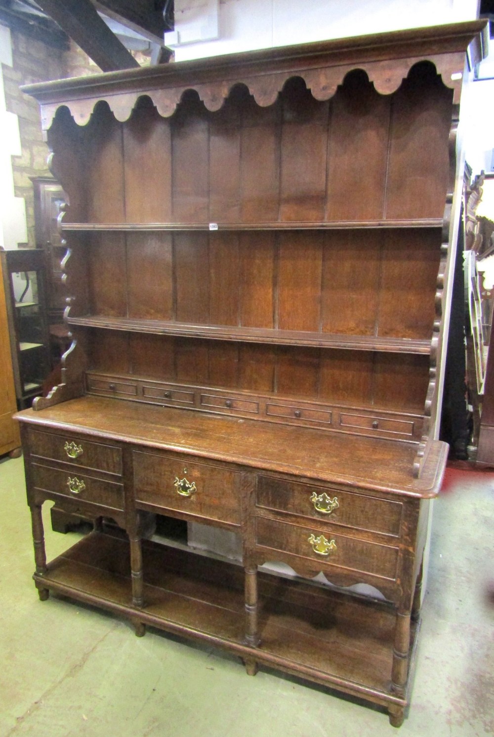 A Georgian oak cottage dresser, the lower section enclosed by an arrangement of five drawers over an