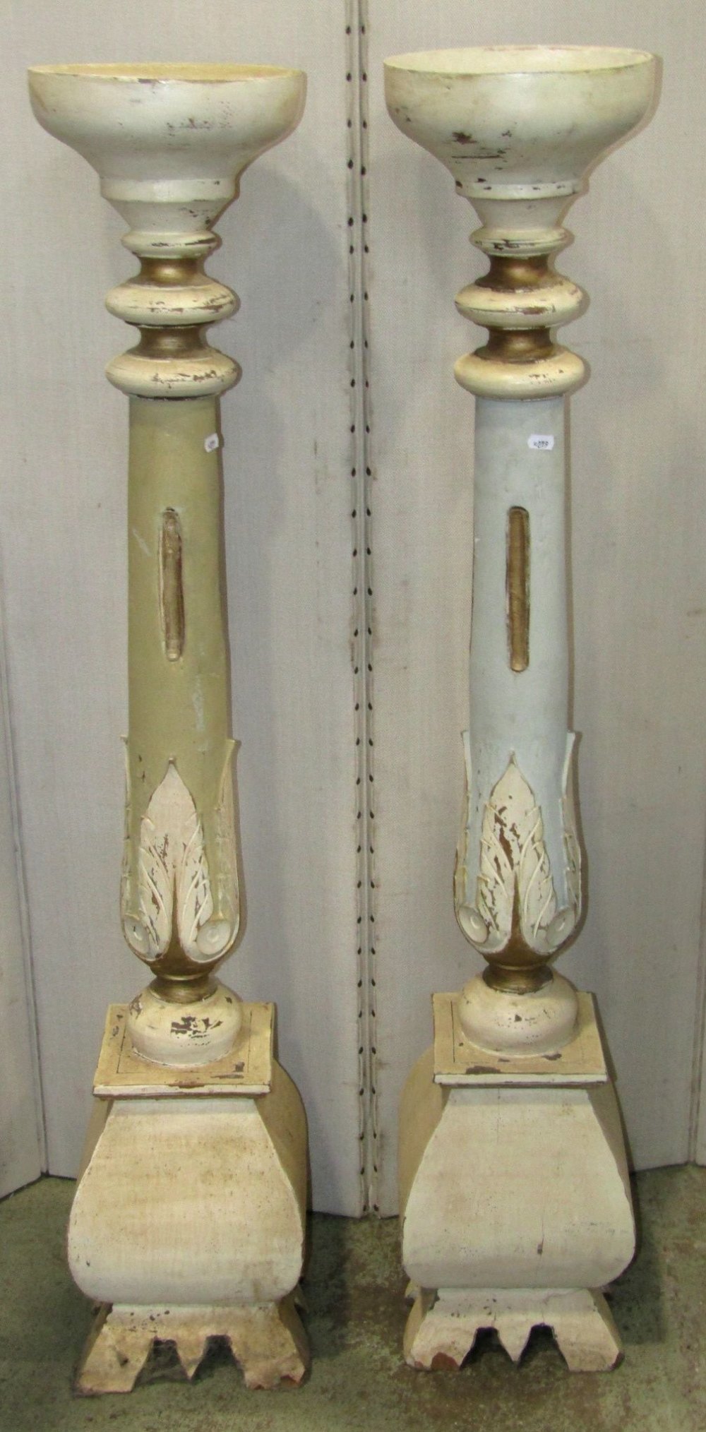 A pair of painted hardwood torcheres with carved foliate detail