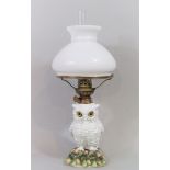Continental porcelain figural oil lamp in the form of a standing owl, the opaline shade on a brass