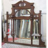 An art nouveau/crafts walnut overmantel mirror, the moulded and shaped frame enclosing numerous