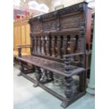 An antique oak settle, the raised and partially panelled back with geometric mouldings, lions