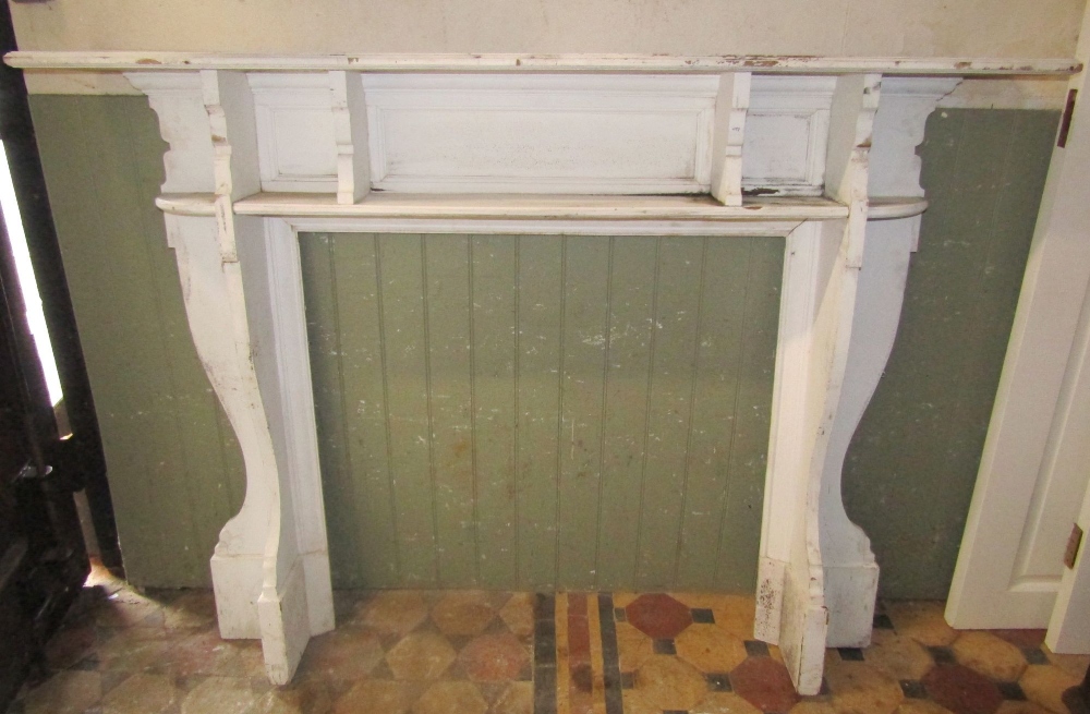 An Edwardian walnut fire surround with moulded frame and shaped brackets, the mantle 153 cm wide,