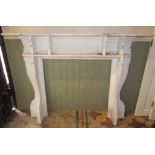 An Edwardian walnut fire surround with moulded frame and shaped brackets, the mantle 153 cm wide,