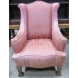 An antique Georgian style armchair, with shallow winged back, down swept arms and upholstered