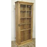 A small rustic stripped pine framed side cabinet enclosed by a segmented glazed panelled doors,