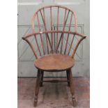 A primitive Windsor stick back elbow chair in mixed woods, the circular seat raised on four turned